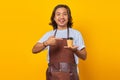 Portrait of positive cheerful man holding paper cup with finger showing sales discount over yellow background Royalty Free Stock Photo