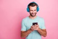 Portrait of positive cheerful man music lover listen radio songs have headset use smartphone browse internet choose Royalty Free Stock Photo