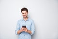 Portrait of positive cheerful man stand copyspace have fun use his smartphone type new post in blog enjoy feel content