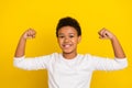 Portrait of positive confident pupil arms demonstrate flexing biceps isolated on yellow color background