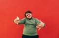 Portrait of a positive curly overweight man on a red background, dancing with a smile on his face and looking at the camera. Fat Royalty Free Stock Photo