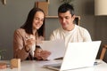 Portrait of positive delighted man and woman sitting at table together in front of laptop, working together with papers, studying Royalty Free Stock Photo