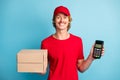 Portrait of positive deliveryman hold two boxes pos terminal wear hat isolated on blue color background