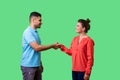 Portrait of positive friendly man and woman in casual wear shaking hands. isolated on green background, indoor studio shot Royalty Free Stock Photo