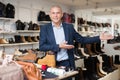 Portrait of positive friendly salesman inviting to shoe store