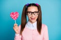 Portrait of positive funny funky girl high school student hold heart shape lollipop want eat lick lips tongue wear good