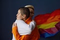 Portrait of positive lesbian woman in friendly embrace on rainbow flag