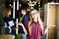 Portrait of a positive looking young woman standing with her open palms with coworkers talking in the background. Royalty Free Stock Photo