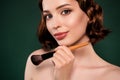 Portrait of positive lovely good looking female makeup artist use foundation brush isolated on green color background Royalty Free Stock Photo