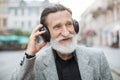 Positive senior man listening music in headphones outdoors Royalty Free Stock Photo