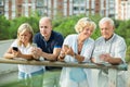 Positive mature couples holding gadgets in park Royalty Free Stock Photo