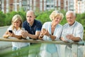 Portrait of positive mature couples using gadgets in park Royalty Free Stock Photo