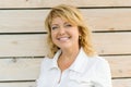 Portrait positive mature middle-aged woman smiling close-up. Blonde woman, outdoor wooden background