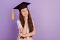 Portrait of positive minded girl look empty space finger chin wear bachelor hat think on purple background