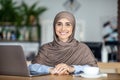 Portrait of positive muslim girl freelancer working at cafe