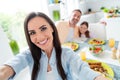 Portrait of positive peaceful parents small daughter make selfie enjoy tasty domestic dish dining room table indoors