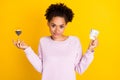 Portrait of positive pretty dark skin lady hold money sandglass look camera isolated on yellow color background