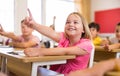 Girl raising hand to answer during lesson at classroom Royalty Free Stock Photo