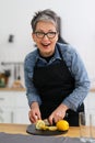 Portrait of a positive senior woman cutting and slicing lemon for homemade lemonade Royalty Free Stock Photo