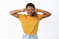 Portrait of positive smiling african american woman shows peace, v-sign near eyes and looking happy, optimism and Royalty Free Stock Photo
