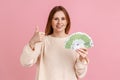 Woman holding many euro banknotes and showing thumb up to camera, satisfied of winning lottery. Royalty Free Stock Photo