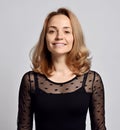 Portrait of positive, smiling woman with long curly blonde hair wearing black lace blouse, dress looking at camera Royalty Free Stock Photo