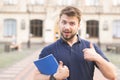 Portrait of a positive student standing with books in his hands against the background of the building and smiling Royalty Free Stock Photo