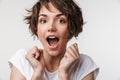 Portrait of positive woman with short brown hair in basic t-shirt rejoicing and clenching fists Royalty Free Stock Photo