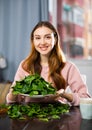 Portrait of a positive young woman with a plate of spinach