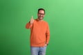 Portrait of positive young handsome entrepreneur showing thumbs up sign over green background
