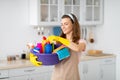 Portrait of positive young maid holding cleaning supplies at kitchen Royalty Free Stock Photo