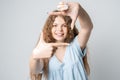 Portrait positive of young woman with curly long hair with cheerful expression. Gesturing finger frame Royalty Free Stock Photo