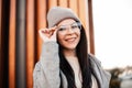 Portrait positive young woman with cute smile in stylish glasses in fashionable knitted hat in vintage coat on the street on Royalty Free Stock Photo