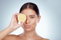 Portrait of pouting woman holding ripe lemon over her eye while posing topless with copyspace. Caucasian model isolated