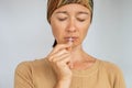 Portrait praying middle aged religious woman wearing headscarf praying and kissing christian orthodox crucifix