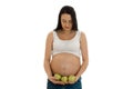 Portrait of pregnant brunette in white shirt twith green apples in hands looking down isolated on white background