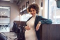 Portrait Of Pregnant Businesswoman Holding Bump Working In Modern Office