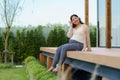 Portrait of pregnant Happy Asian woman sitting on terrace at home and using smart phone for listening music in headphones Royalty Free Stock Photo