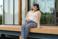 Portrait of pregnant Happy Asian woman sitting on terrace at home and using smart phone for listening music in headphones Royalty Free Stock Photo