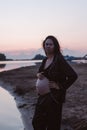 Portrait of pregnant woman on beach. Romantic photo of attractive young brunette in unbuttoned dark pajamas on beach Royalty Free Stock Photo
