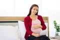 Pregnant woman sitting on bed and looking at her ultrasound image of her child in her belly Royalty Free Stock Photo