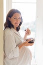 Portrait of pregnant woman eating healthy bowl of fruit in kitchen Royalty Free Stock Photo