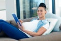 Portrait of pregnant woman relaxing on sofa with her digital tablet Royalty Free Stock Photo
