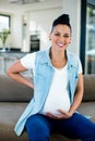 Portrait of pregnant woman sitting on sofa with and on stomach Royalty Free Stock Photo