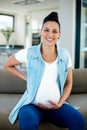 Portrait of pregnant woman sitting on sofa with and on stomach Royalty Free Stock Photo