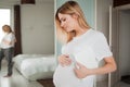 Portrait of pregnant woman stroking her tummy, with a book under her arm against the background of reflection in mirror. Royalty Free Stock Photo