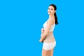 Portrait pregnant woman in underwear wearing pregnancy belt at blue background with copy space. Close up of orthopedic abdominal Royalty Free Stock Photo