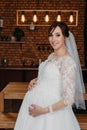 portrait of a pregnant woman in a white wedding dress. a pregnant woman with flowers in her hand in studio. Royalty Free Stock Photo