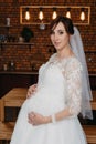 portrait of a pregnant woman in a white wedding dress. a pregnant woman with flowers in her hand in studio. Royalty Free Stock Photo