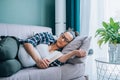 Portrait of pregnant young woman with glasses sleeping holding book on sofa near flowerpot and glass of water on table. Royalty Free Stock Photo